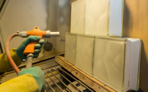 Human hands in sandblasting chamber holding a sandblaster gun